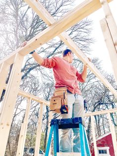 a man is standing on a ladder working on the framing of a house that's under construction