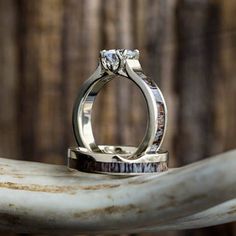 two wedding rings sitting on top of a white marble slab with wood in the background