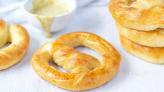 several bagels are stacked on top of each other with dipping sauce in the background