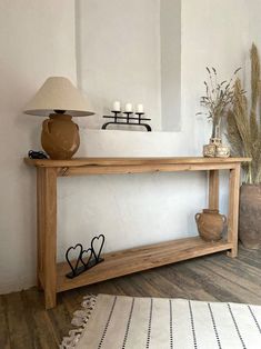 a wooden table sitting on top of a hard wood floor next to a lamp and potted plant