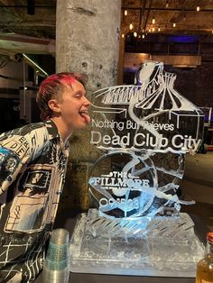 a young man sticking his tongue out in front of a dead cup city ice sculpture