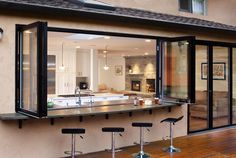 an outdoor bar with four stools in front of it and a kitchen behind it