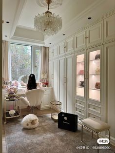 a woman is sitting in a room with white furniture and chandelier hanging from the ceiling