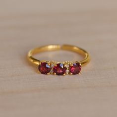 Dainty garnet and diamond gold ring.  Three gorgeous little faceted garnet gemstones flanked with two tiny diamonds besides the middle one and set in gold vermeil.  The open band is adjustable allowing it to be sized up a size. This ring makes such a special gift for that classic woman.  -  M A T E R I A L S - 925 Sterling Silver Gold plated  - G E M S T O N E   P R O P E R T I E S -  Diamond: love, strength, prosperity  Garnet  - S I Z E - Refer to https://pebblesandchance.com/pages/ring-sizing Garnet Open Ring Birthstone Gift, Garnet Open Ring Birthstone Ring, Garnet Birthstone Open Ring, Adjustable Elegant Ruby Ring, Elegant Red Ruby Toe Ring, Gold Garnet Open Ring, Gold Ruby Ring With Cubic Zirconia For Gift, Dainty Garnet Rings For Gift, Dainty Garnet Rings As Gift