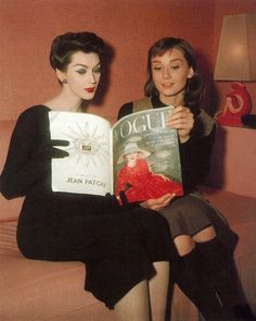 two women sitting on a couch holding books