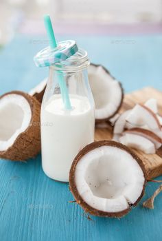 coconuts and milk on a blue wooden table with a straw in a bottle - stock photo - images