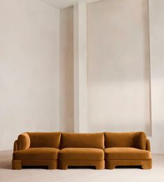 an orange couch sitting on top of a white floor next to a tall wall in a living room