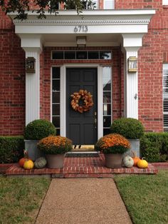 a front door with two planters filled with pumpkins