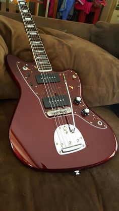 a red electric guitar sitting on top of a couch