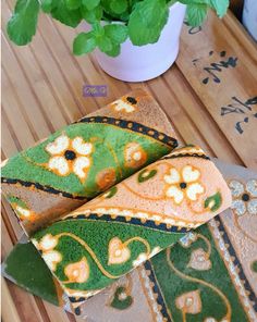 a plant is sitting on a table next to some decorative rugs that are green and orange