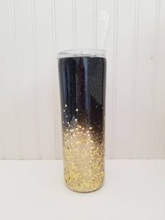 a black and gold colored cup sitting on top of a white table next to a wall