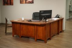 an office desk with a computer on it in the middle of a wood floored room