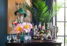 a bar cart filled with liquor bottles and glasses next to a potted palm tree