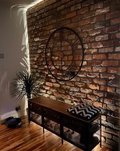 a living room with a brick wall and wooden flooring next to a planter