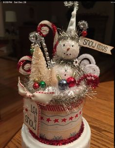 a cake decorated with silver and red decorations on top of a wooden table next to a sign that says snow kisses