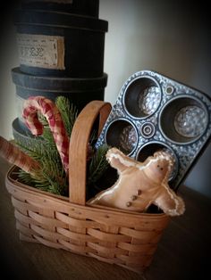 a wooden basket filled with candy canes and other holiday treats next to muffin tins