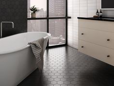 a white bath tub sitting in a bathroom next to a sink and window with city view