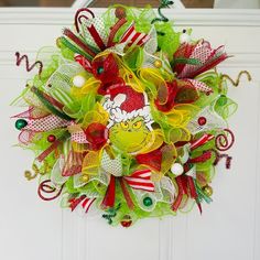 a christmas mesh wreath hanging on a door with the grinly face and candy canes