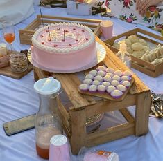 a pink cake sitting on top of a wooden table covered in cupcakes and muffins