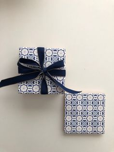 two blue and white wrappings tied together with a bow on the top one is square