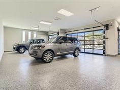 two range rovers are parked in an empty garage