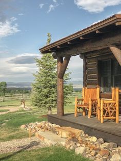 a log cabin sitting on top of a grass covered field next to a wooden deck