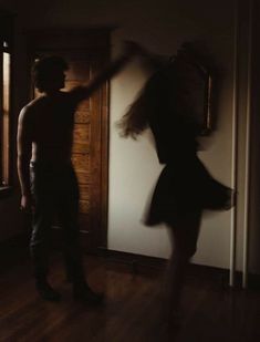 a man standing next to a woman in front of a door with her arms outstretched