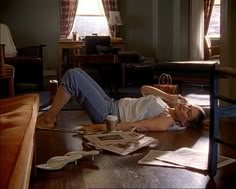 a woman laying on the floor next to a table with papers and coffee cup in front of her