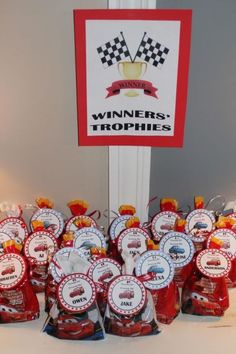 there are many red and white trophies on display in front of a sign that says winners trophies