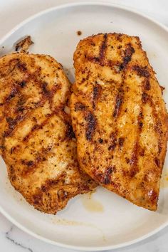 two pieces of grilled chicken on a white plate