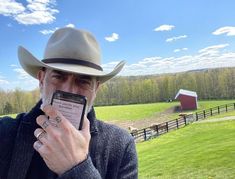 a man in a cowboy hat is holding up his cell phone to take a selfie