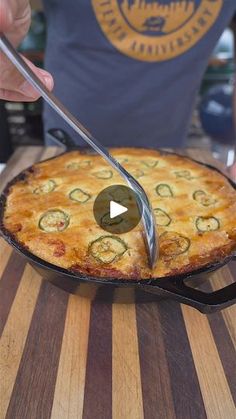 a person cutting into a pizza on top of a wooden table