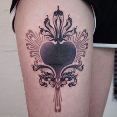 a woman's thigh with an ornate heart tattoo design on the side of her leg