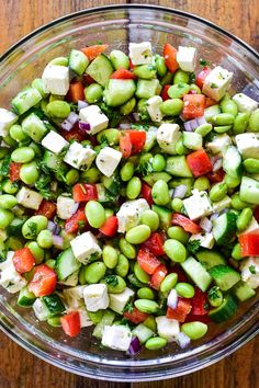 a glass bowl filled with vegetables and feta cheese