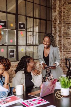 three women sitting at a table and one woman is looking at her tablet while the other looks on