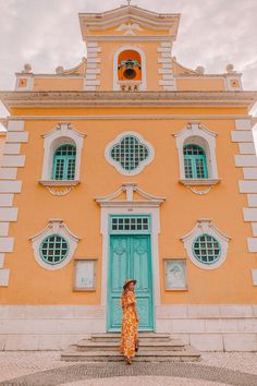 a woman standing in front of a yellow building