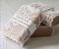 two soap bars sitting on top of a white tablecloth covered in lacy fabric and paper