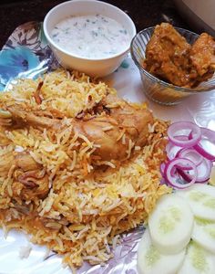 a plate with rice, meat and vegetables on it next to bowls of sauces