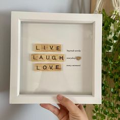 someone is holding up a scrabble frame with the words live laugh love spelled in it