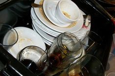 a pile of dirty dishes and glasses on top of a table with utensils