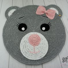 a crocheted bear rug with a pink bow on it