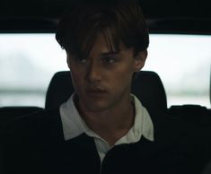 a young man sitting in the back seat of a car