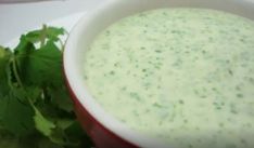 a red and white bowl filled with dip next to cilantro