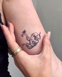 a woman's arm with a tattoo on it and an octopus in the shape of a heart