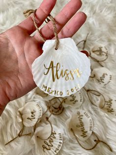 a hand holding a personalized seashell ornament with the name alossy on it