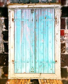 an old blue door is open in front of a brick wall and wood flooring