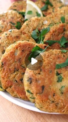 several crab cakes on a white plate with lemon wedges and parsley garnish