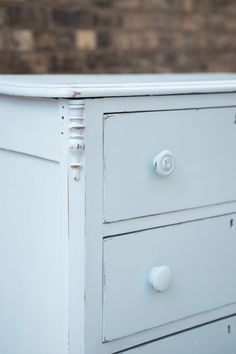 a white dresser with two drawers and knobs