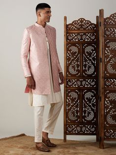 Vastramay Men's Peach Sequined Indo Sherwani Set Make a grand statement with this stunning peach sequined sherwani set. Featuring a meticulously crafted sherwani with a cream kurta and pants, this ensemble is perfect for special occasions. Key Features Peach sequined embellished sherwani Cream colored kurta with mandarin collar Comfortable cream pants with elasticated waistband Specifications Sleeve Length - Long Sleeves Shape - Straight Top Hemline - Straight Neck - Mandarin Collar Top Length - Pink Traditional Naqshi Sherwani, Formal Pink Bandhgala With Intricate Embroidery, Designer Pink Sherwani Straight Kurta, Pink Sherwani With Intricate Embroidery, Designer Pink Sherwani With Dabka Detailing, Pink Raw Silk Sherwani With Traditional Drape, Designer Pink Sherwani With Dabka, Bollywood Pink Sherwani With Chikankari Embroidery, Pink Naqshi Kurta For Reception