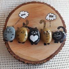 four cats painted on rocks sitting on top of a wooden slice